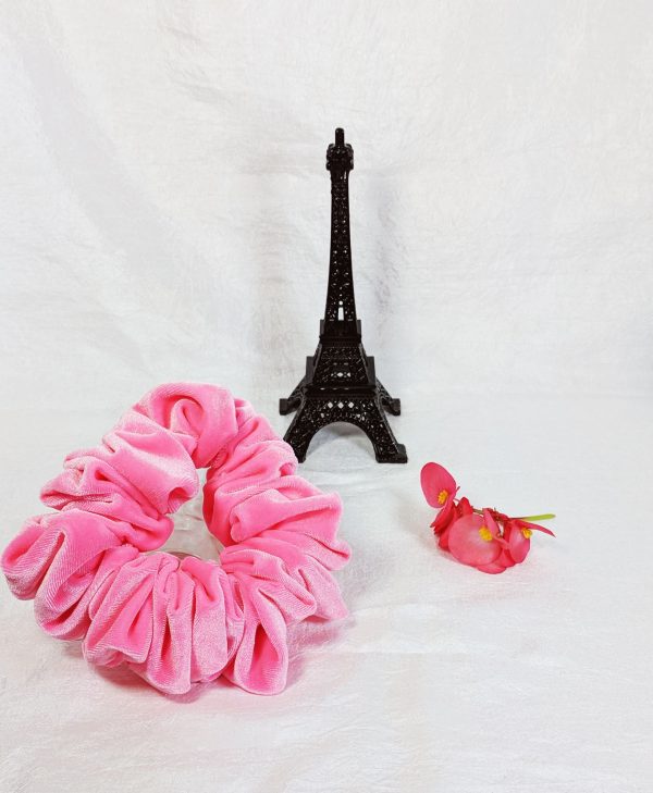Full size neon pink velvet scrunchy on a white background. The scrunchy is made of soft velvet fabric and has a medium size that is perfect for creating full buns or half-up styles. The vibrant pink color adds a pop of color to any hairstyle.
